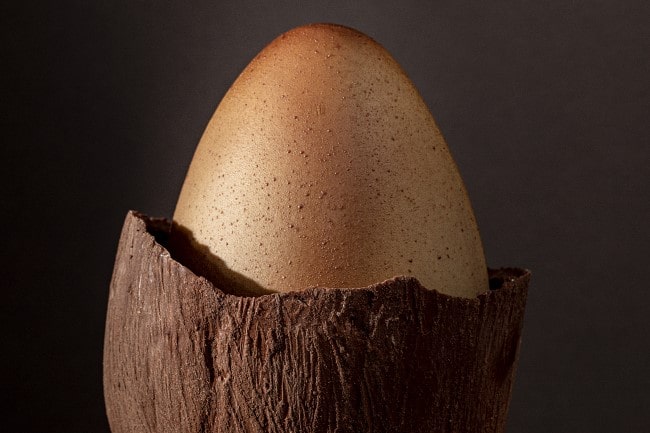 A boiled egg inside of a cracked chocolate egg