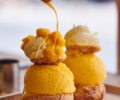 Profiterole filled with Passionfruit ice cream with whipped cream and fruit sauce with pieces of mango