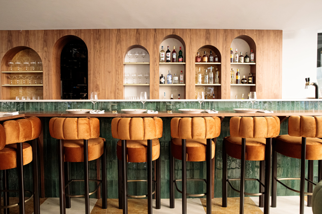 Restaurant bar with plush bar stools and green tiles