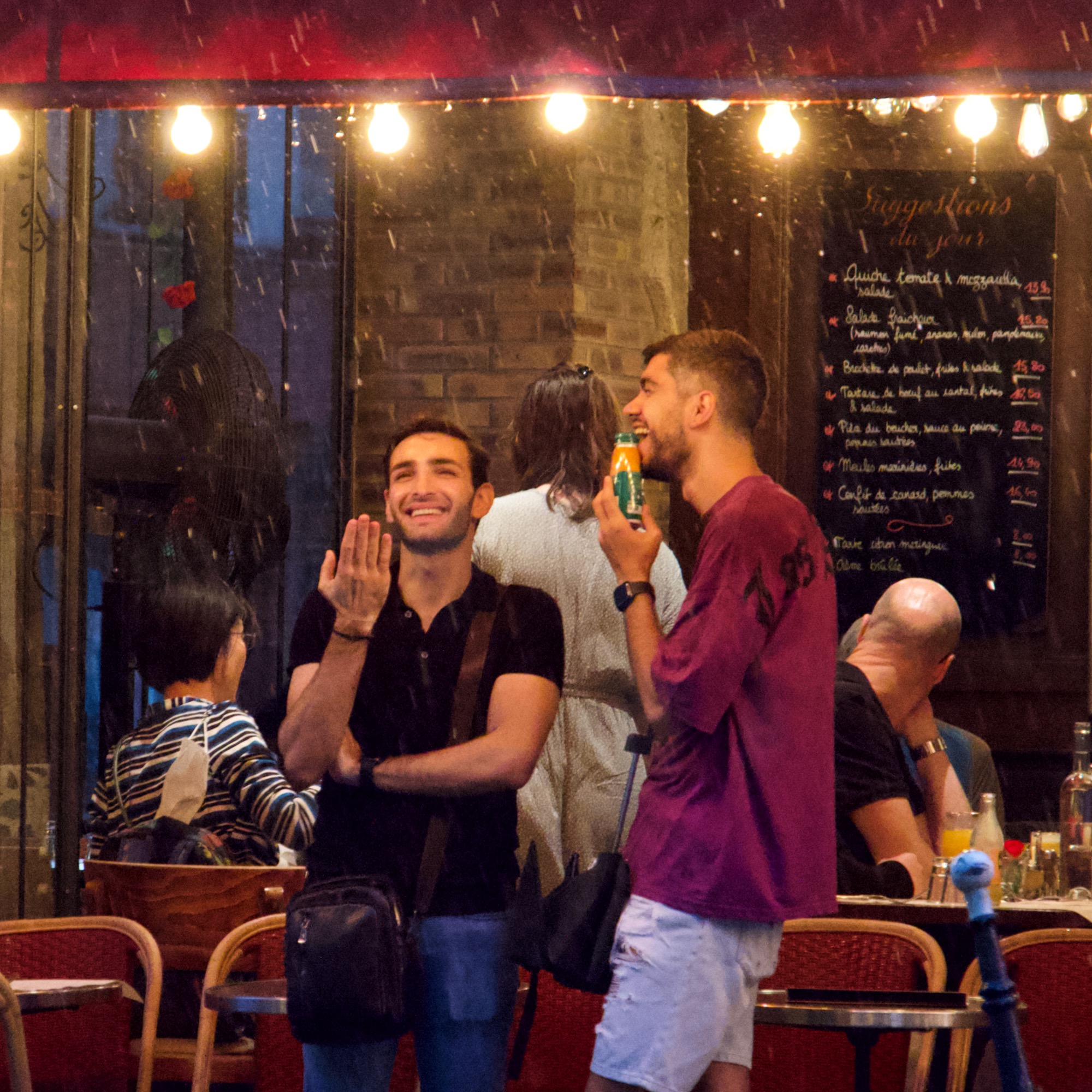 A photo of two people under a canopy waiting for the rain to stop