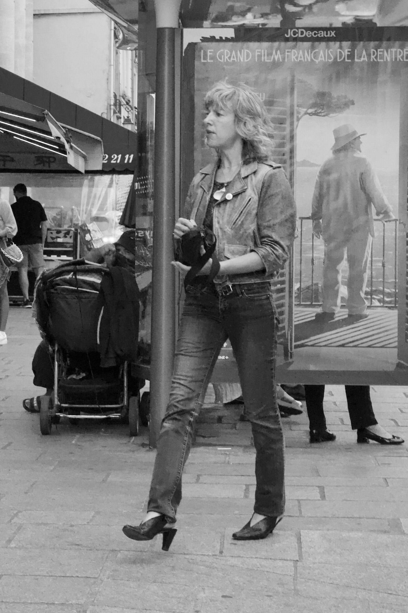 A photo of a woman walking in front of a poster