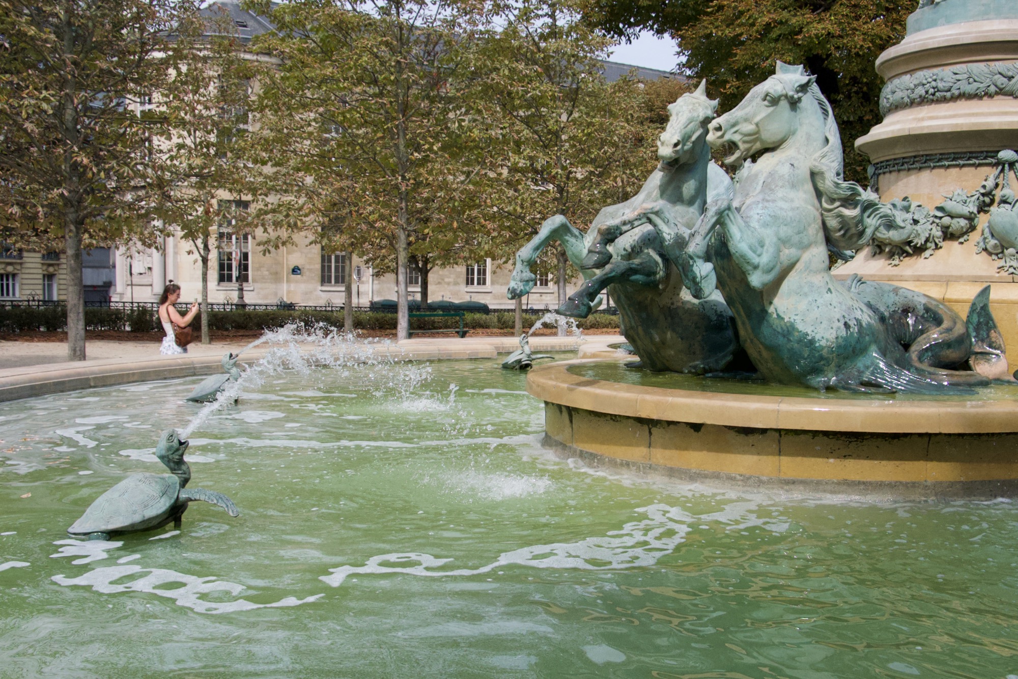 A water feature statue of a tortoise spraying water at horses