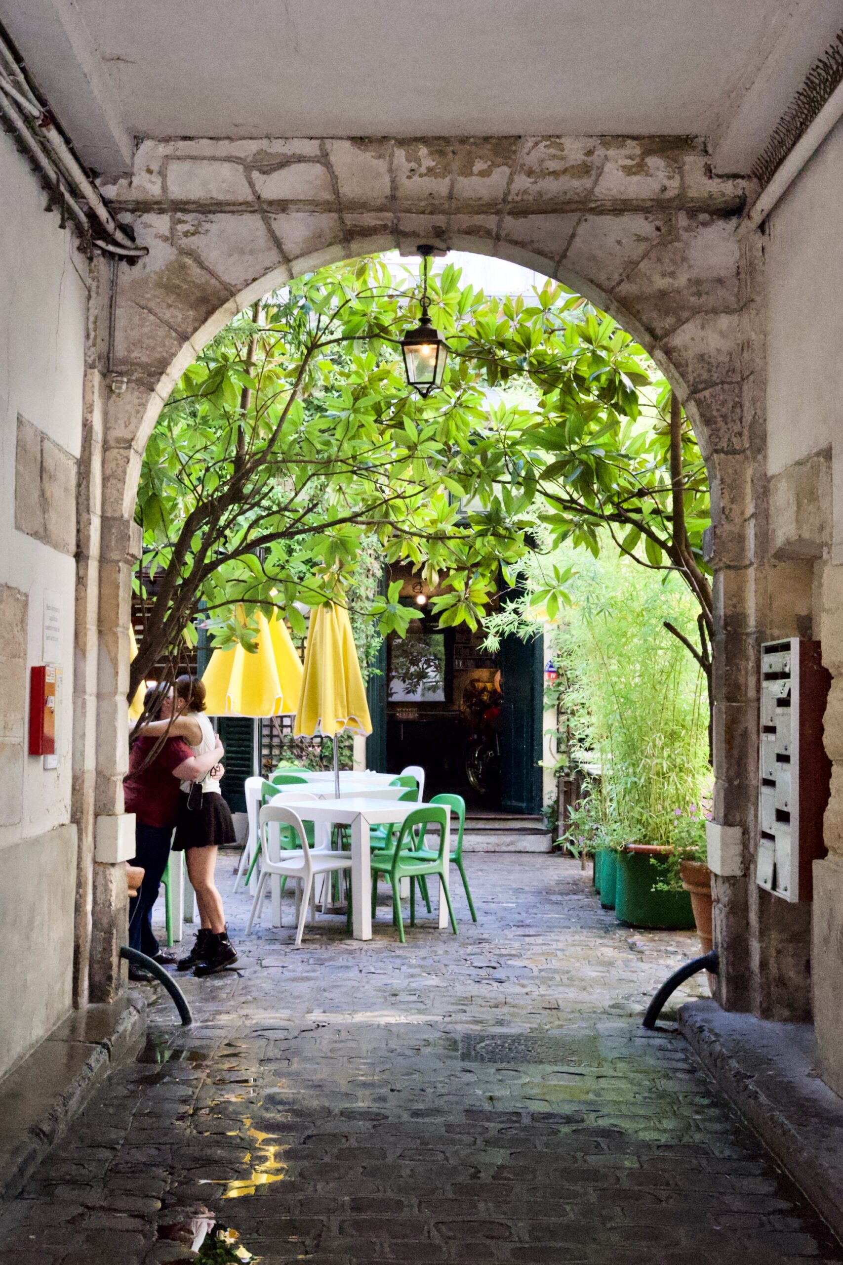 A photo of two people hugging beneath trees at the end of an ally