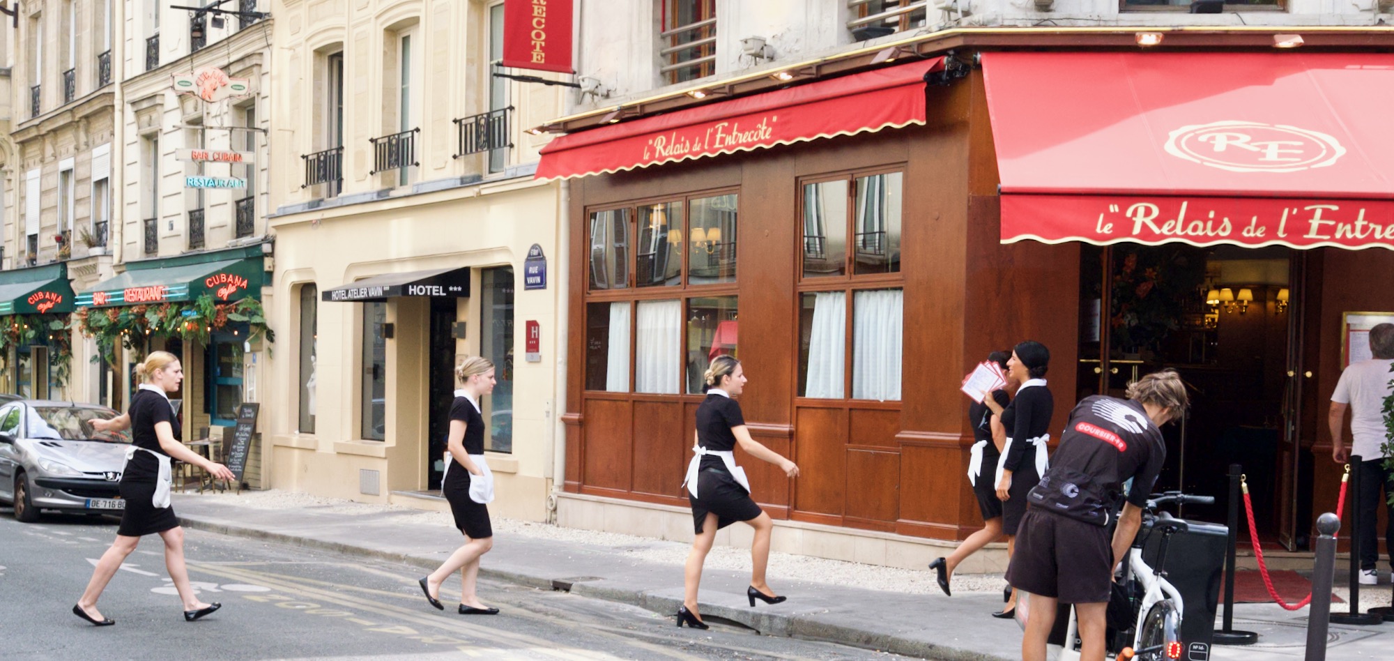 A photo of waitresses walking across the road towards le Relais de l' Entrecote